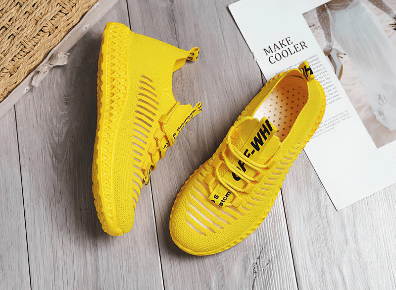 Bright yellow mesh lace-up sneakers for women with flat bottoms on a wooden floor, perfect for casual wear and comfort.